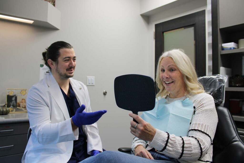 Dr. Andrew Mancin showing a smiling patient her results at OP Implant Dental in Overland Park, KS
